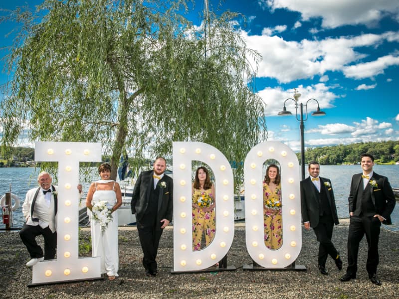 Newlyweds and wedding party by I Do letters.