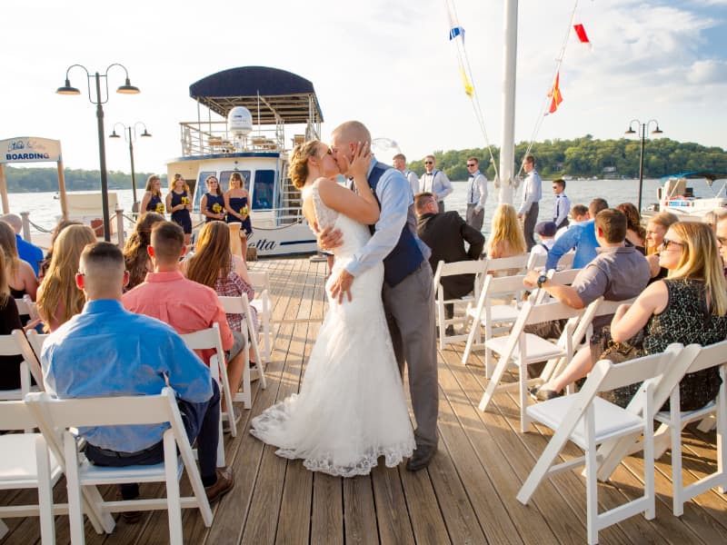 Man and woman kissing on the dock, surrounded by guests