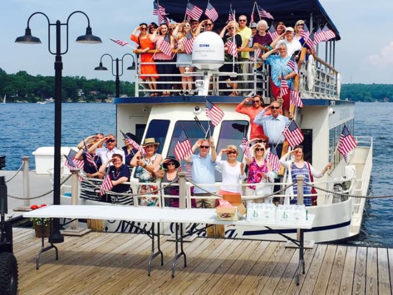 Cruise-goers with American flags saluting and smiling
